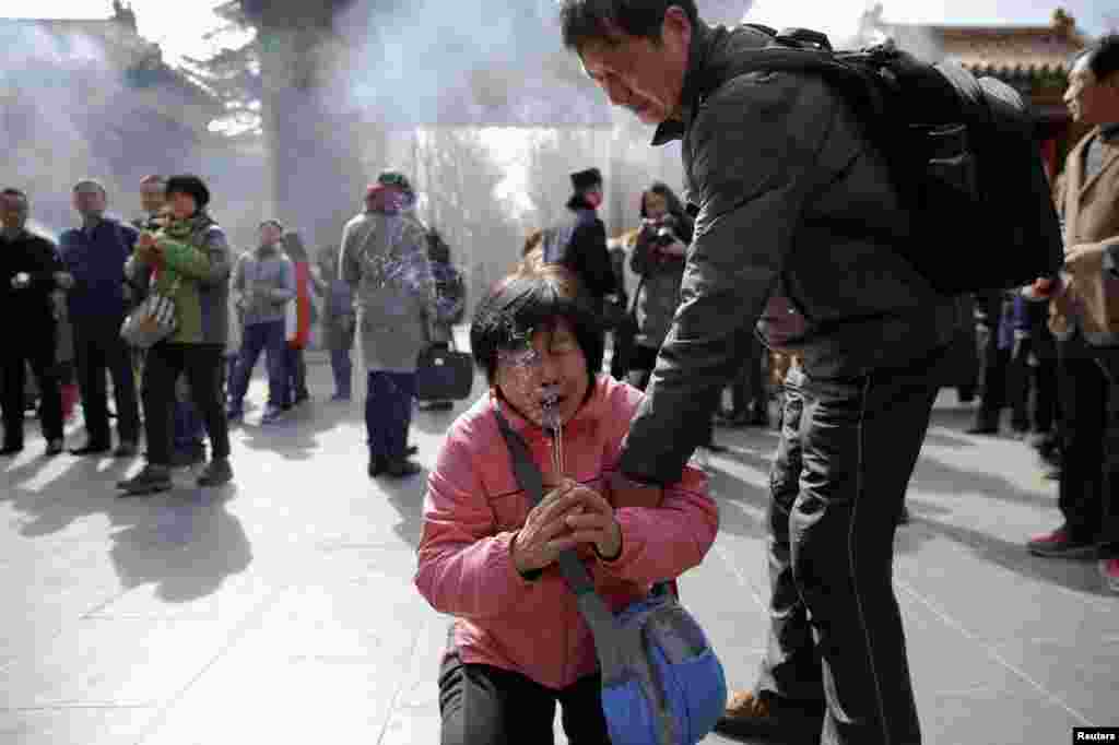 A woman cries as relatives of passengers onboard of Malaysia Airlines flight MH370 which went missing in 2014, burn incense sticks and pray at Lama Temple in Beijing, China.