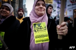 FILE - A Muslim woman holds a poster during a protest against Donald Trump in New York, Dec. 20, 2015.