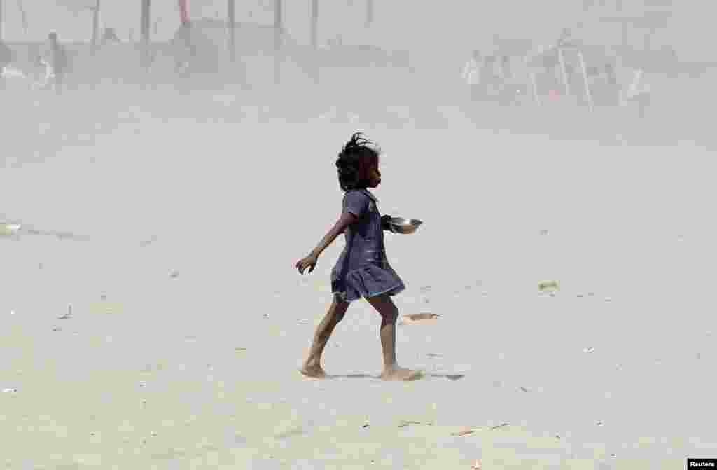 A girl walks amidst a dust storm on the banks of the Ganges river in Allahabad, India.