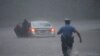 Un policier se précipite pour aider un automobiliste en détresse pendant la tempête tropicale Isaias, le mardi 4 août 2020, à Philadelphie, en Pennsylvanie. (AP Photo/Matt Slocum)