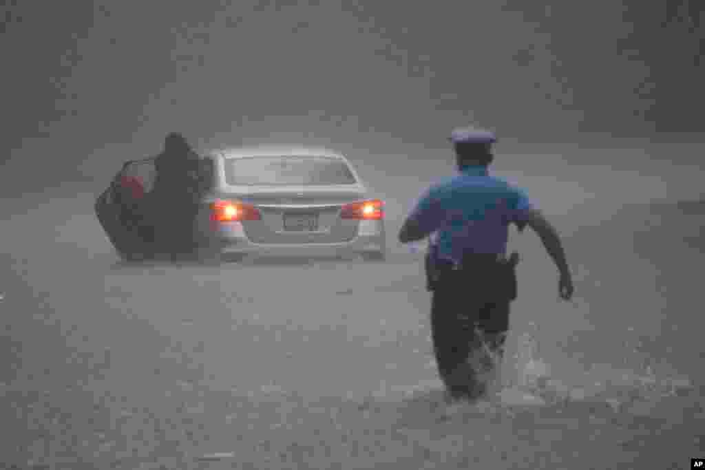 A police officer runs to help a motorist caught in flooding during Tropical Storm Isaias in Philadelphia, Pennsylvania.