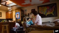 In this Nov. 28, 20017 photo, TC Bell sits with his two daughters Dagny, 8 and Emma, 4 before they get ready for school, at their home in Denver. Bell's daughters are recipients of the Children's Health Insurance Program or CHIP.