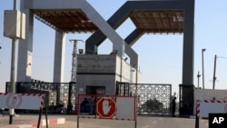 Palestinian security officers and residents sit at the closed entrance of the Rafah border crossing with Egypt southern Gaza Strip, July 17, 2018. Israel closed the Baz border crossing Sunday as Egyptian mediators worked to broker a cease-fire.