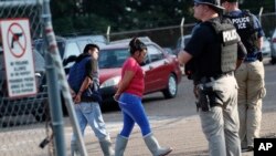 Dos personas son detenidas en una planta de Koch Foods Inc. en Morton, Mississippi, el miércoles 7 de agosto de 2019.