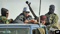 Libyan rebels who are part of the forces against Libyan leader Moammar Gadhafi ride on an armed truck near Ras Lanuf, eastern Libya, March 7, 2011