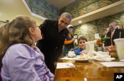 President Barack Obama, accompanied by Senate Minority Whip Richard Durbin of Illinois, right, stops to greet Anna Moser, 9, and brother Grant Moser, 6, right, during an unscheduled stop to the Feed Store, a sandwich shop in Springfield, Ill., Feb. 10, 2016.