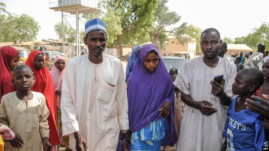 Msichana aliyeachiwa huru na Boko Haram akitembea na baba yake (kushoto) katika eneo la Dapchi Machi 21, 2018.