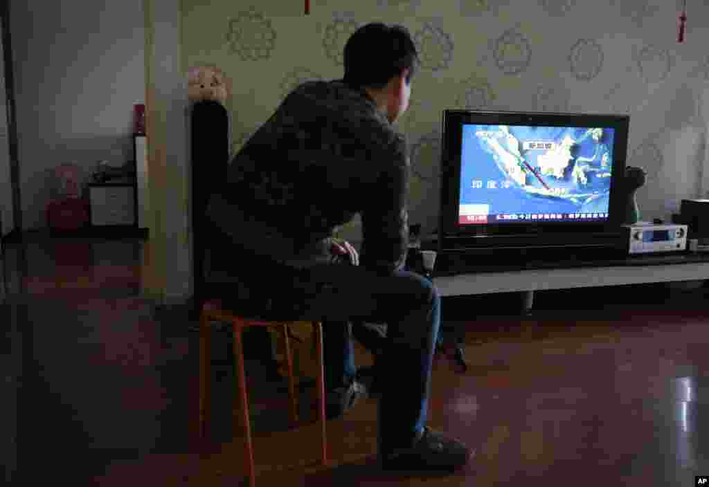 Jiang Hui, a relative of passengers on board the Malaysia Airlines Flight 370 that went missing on March 8, 2014, watches a TV news about a missing AirAsia flight QZ8501, during their year-end gathering, at his house in Beijing, China, Dec. 28, 2014.