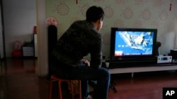 Jiang Hui, a relative of passengers on board the Malaysia Airlines Flight 370 watches TV news about a missing AirAsia flight QZ8501, at his house in Beijing, China, Dec. 28, 2014.