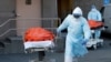 နယူးယောက်တွင် ကိုရိုနာဗိုင်းရပ်စ်ကြောင့် သေဆုံးသူများကို သယ်လာသည့် ကျန်းမာရေးဝန်ထမ်းများ။ (ဧပြီ ၄၊ ၂၀၂၀)