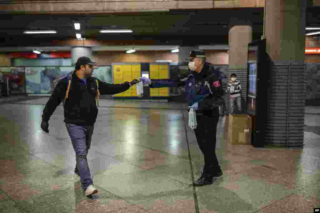 یک پلیس محلی در حال توزیع ماسک صورت در ایستگاه ترن آتوچا در مادرید، اسپانیا