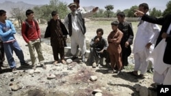 Afghans stand around the bloodstains at the scene of a suicide attack in Kapisa, northeast of Kabul, Afghanistan, June 15, 2011