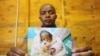 Brown Lekekela, a community leader and counselor in the Johannesburg settlement of Diepsloot, holds the photograph of a baby he helped rescue from neglect and abuse. 