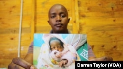 Brown Lekekela, a community leader and counselor in the Johannesburg settlement of Diepsloot, holds the photograph of a baby he helped rescue from neglect and abuse. 