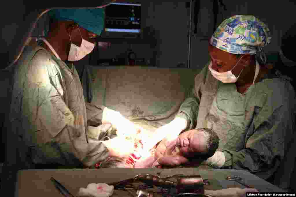 Baby born via emergency Caesarean section; left: general surgeon, right: nurse anaesthetist.