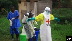 FILE - A health worker sprays disinfectant on his colleague after working at an Ebola treatment centrer in Beni, eastern DRC, Sept 9, 2018.