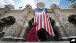 穆斯林妇女走过吉隆坡独立广场悬挂马来西亚国旗的苏丹阿都沙末大厦