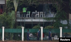 Policemen patrol outside the Holey Artisan Bakery and the O'Kitchen Restaurant as others inspect the site after gunmen attacked, in Dhaka, Bangladesh, July 3, 2016.