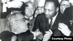 U.S. President Lyndon Johnson, left, and civil rights leader Martin Luther King Jr. shake hands at the Voting Rights Act's signing in the Capitol, Washington, August 6, 1965. (Creative Commons)