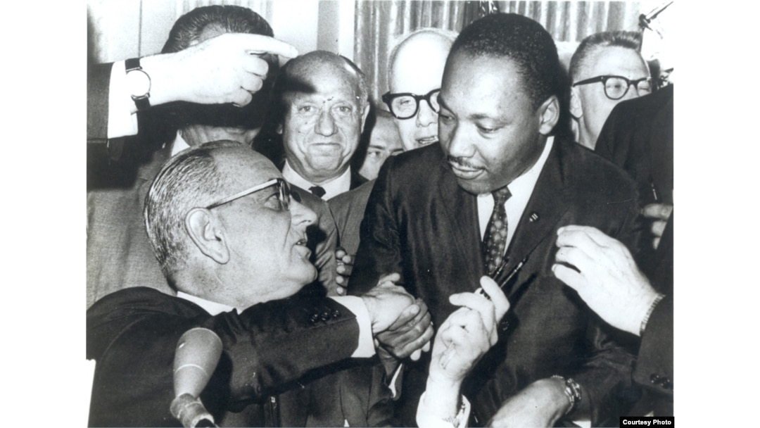 FILE - Photograph of President Lyndon Johnson signing the Voting Rights Act as Martin Luther King, Jr., with other civil rights leaders in the Capitol Rotunda, Washington, DC, August 6, 1965. (Creative Commons)
