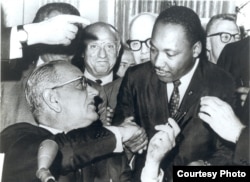 FILE - Photograph of President Lyndon Johnson signing the Voting Rights Act as Martin Luther King, Jr., with other civil rights leaders in the Capitol Rotunda, Washington, DC, August 6, 1965. (Creative Commons)