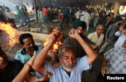 A man mourns next to the burning pyre of a family member who died after a train traveling at high speed ploughed through a crowd of people, at a cremation site in Amritsar, India, Oct. 20, 2018.