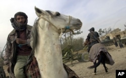 FILE - Militiamen loyal to Afghan warlord Abdul Rashid Dostum ride horses near Mazar-i-Sharif in northern Afghanistan, Nov. 28, 2001.