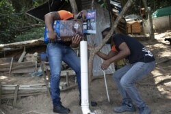 Volunteers from Animal Heart Protectors fill a dispenser with food for cats on Furtada Island, popularly known as “Island of the Cats,” in Mangaratiba, Brazil, Tuesday, Oct. 13, 2020. (AP Photo/Silvia Izquierdo)