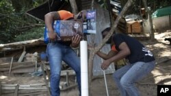 Volunteers from Animal Heart Protectors fill a dispenser with food for cats on Furtada Island, popularly known as “Island of the Cats,” in Mangaratiba, Brazil, Tuesday, Oct. 13, 2020. (AP Photo/Silvia Izquierdo)