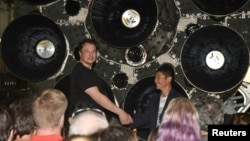 FILE - SpaceX CEO Elon Musk (L) shakes hands with Japanese billionaire Yusaku Maezawa who was introduced as the first SpaceX private passenger to circle the moon, in Hawthorne, California September 17, 2018. (REUTERS/Gene Blevins)