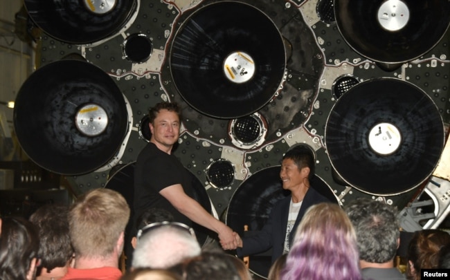 FILE - SpaceX CEO Elon Musk (L) shakes hands with Japanese billionaire Yusaku Maezawa during a press conference about being the first SpaceX private passenger to circle the moon aboard SpaceX’s BFR launch vehicle, in Hawthorne, California September 17, 2020