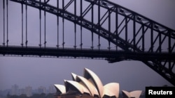 FILE - The sun illuminates the Sydney Opera House as a ferry sails past during a storm at Sydney Harbor in Australia, Nov. 23, 2016. 