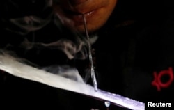 A drug user inhales "shabu," or methamphetamine, at a drug den in Manila, Philippines, Feb. 13, 2017.