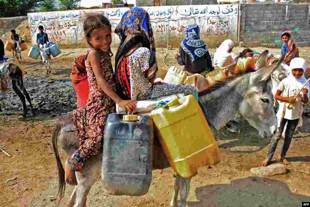 Children riding on donkeys wait to fill their containers with water from a cistern at a temporary camp for the internally displaced in Yemen&#39;s northern Hajjah province, during an extreme heatwave and severe water shortages.