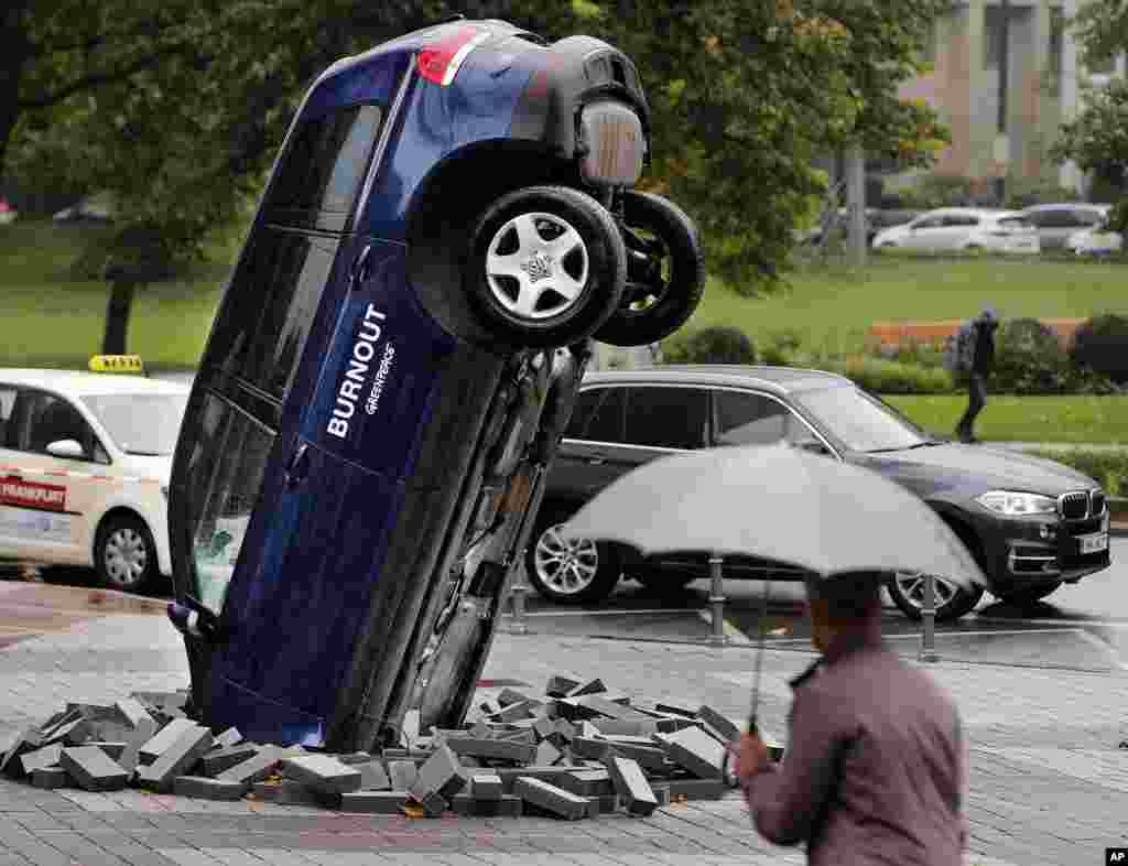 A Volkswagen Touareg stands upside down in front of the fair ground of the IAA Motor Show in Frankfurt, Germany.