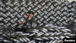 FILE - A woman works on packaging bicycle rim steels for export at a workshop of a company manufacturing sports equipment in Hangzhou, Zhejiang province, China, June 4, 2018. 