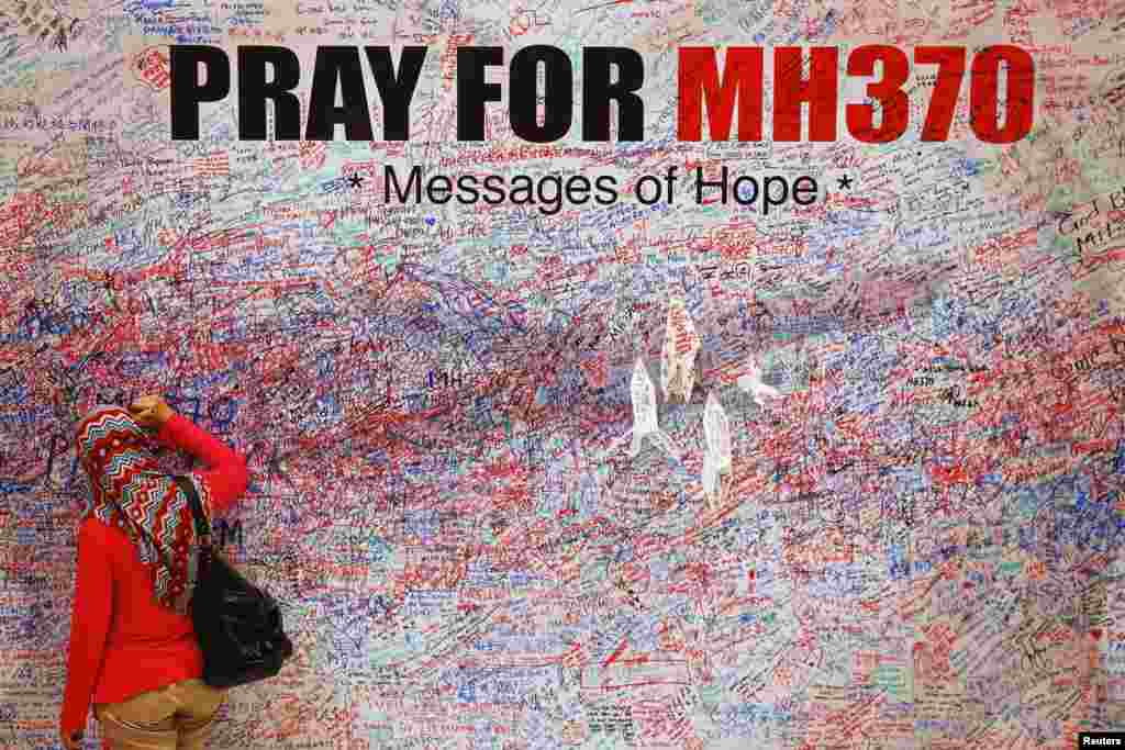 Seorang perempuan meninggalkan pesan dukungan bagi para penumpang pesawat Malaysia Airlines MH370 yang hilang di Kuala Lumpur (16/3). (Reuters/Damir Sagolj)