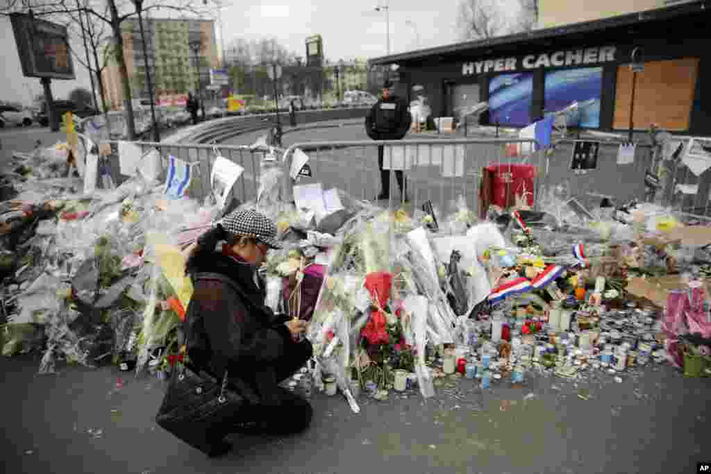 A woman lights a candle outside the kosher grocery where Amedy Coulibaly killed four people in a terror attack, in Paris, Wednesday, Jan. 20, 2015.