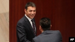 FILE - Macedonian Foreign Minister Nikola Dimitrov, left, shakes hands with Prime Minister Zoran Zeav during a session for the ratification of the deal with Greece, in the parliament in Skopje, Macedonia, June 20, 2018. 