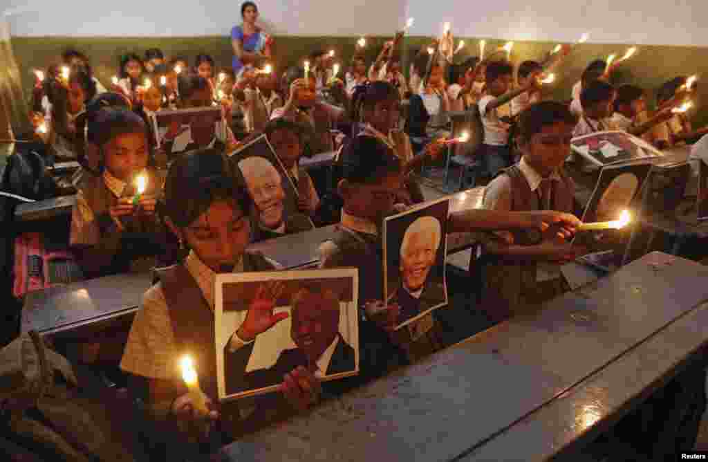 Schoolchildren hold candles and portraits of Nelson Mandela during a prayer ceremony at a school in the western Indian city of Ahmedabad, Dec. 6, 2013.