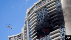 Un helicóptero del Departamento de Bomberos de Honolulu vuela cerca de un incendio quemado en un piso en el complejo de apartamentos Marco Polo, el viernes, julio 14, 2017, en Honolulu.