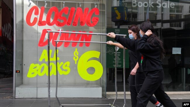 澳大利亚墨尔本商业区的行人走过因新冠疫情而关闭的商店。（2020年8月3日）