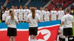 Tim sepak bola puteri Korea Utara menyanyikan lagu kebangsaan mereka sebelum memulai pertandingan melawan Kolombia (25/7).