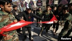 Iraqi Shi'ite protesters tear up a Turkish flag during a rally against Turkey's military presence in northern Iraq, in Basra, Iraq, Oct. 9, 2016.
