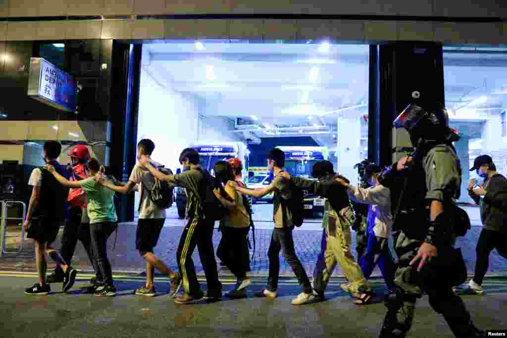 Protesters are escorted by police out of the campus of Hong Kong Polytechnic University (PolyU) during clashes with police in Hong Kong,