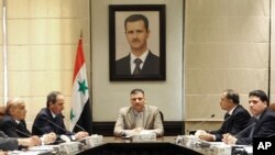叙利亚官方媒体8月5日公布的一张未标日期的照片显示总理里亚德•希贾卜(中)在大马士革的一次会议上讲话。他头上是总统巴沙尔•阿萨德的画像。