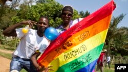 Des hommes ougandais brandissent un drapeau arc-en-ciel: "Rejoignez-nous pour mettre fin au génocide LGBTI (Lesbian Gay Bi Trans Intersex - appelé Kuchu en Ouganda)", comme ils le célèbrent, le 9 août 2014.