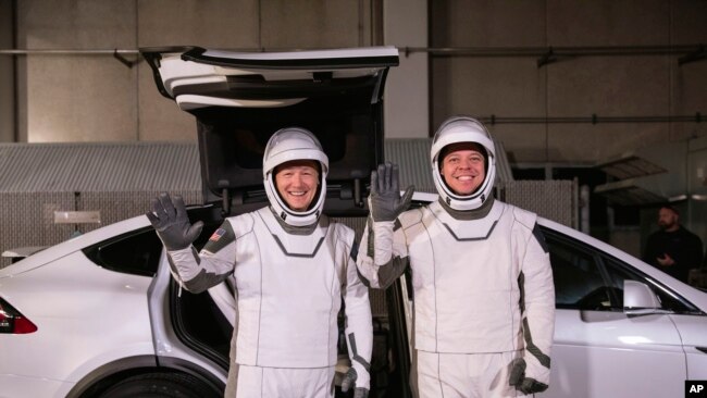 In this Friday, Jan. 17, 2020 photo made available by NASA, astronauts Doug Hurley, left, and Robert Behnken pose in front of a Tesla Model X car during a SpaceX launch dress rehearsal at Kennedy Space Center in Cape Canaveral, Fla. (Kim Shiflett/NASA)