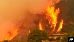 Flames from a back fire rise behind a home in Santa Barbara, Calif. A new red flag warning was scheduled to go into effect Saturday in the fire area because of the predicted return of winds. The Thomas Fire erupted Dec. 4, 2017, a few miles from Thomas Aquinas College.