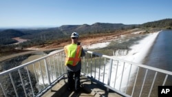 Jason Newton, of the Department of Water Resources, takes a picture of water going over the emergency spillway at Oroville Dam Saturday, Feb. 11, 2017, in Oroville, Calif.